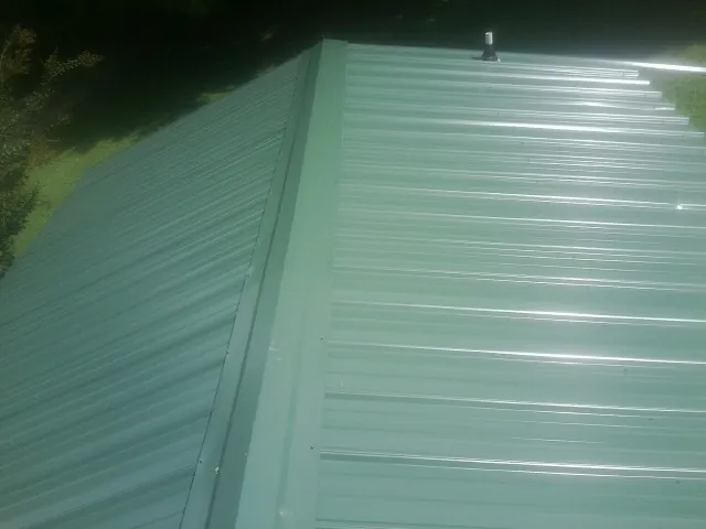 New green metal panels meeting at the ridge of a roof — Flat Roof Repair work by our crew in Strongsville