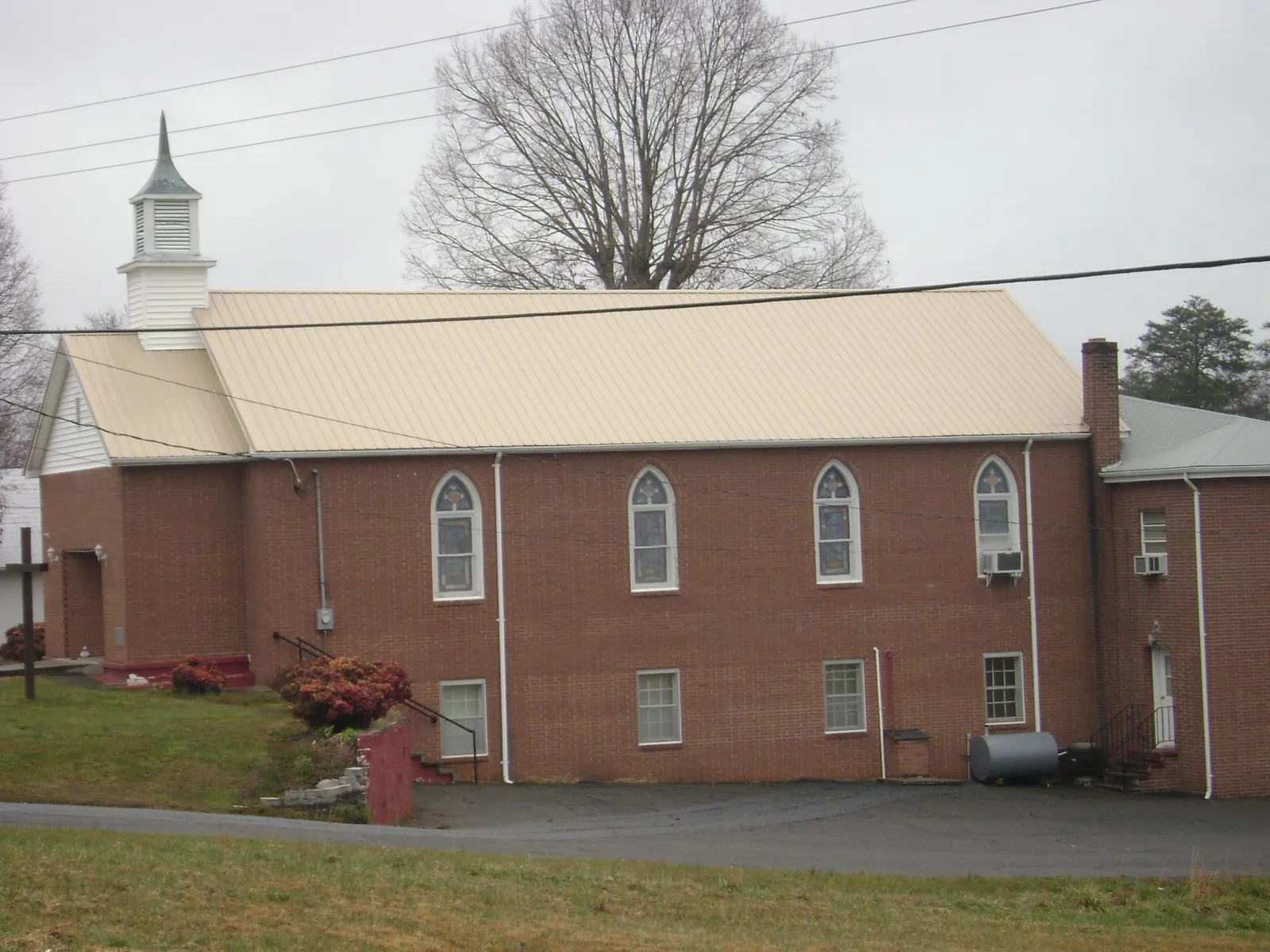 New tan metal roof on a brick church with a white steeple in Strongsville