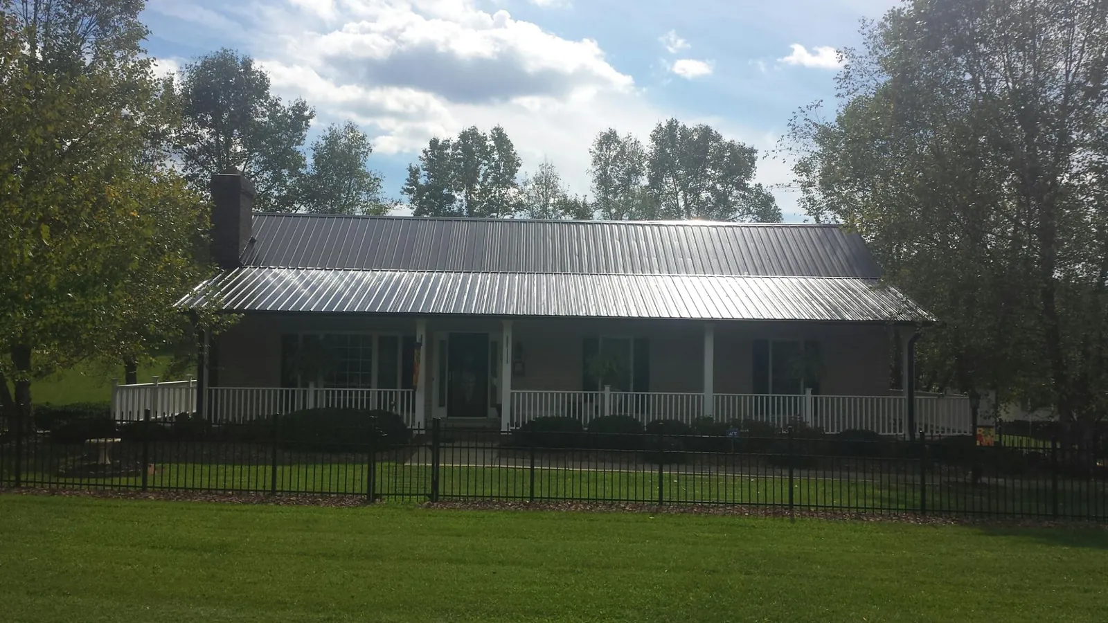 Gray metal roof on a brick ranch with a full width front porch — Gutter Guard Installation work by our crew in Strongsville