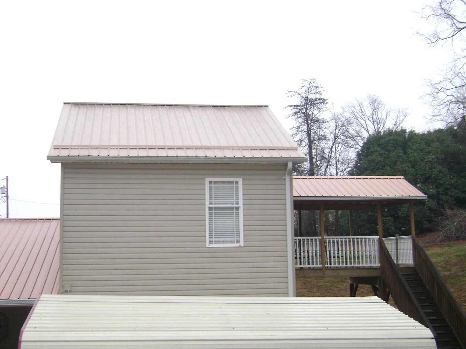 Tan metal roofs on a two story addition and attached porch, from a Roof Replacement job in Strongsville