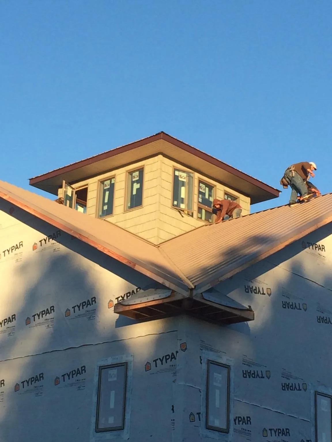 Roofers working around a rooftop cupola on a new metal roof at sunset — Roof Waterproofing in Strongsville by Roofing Brothers